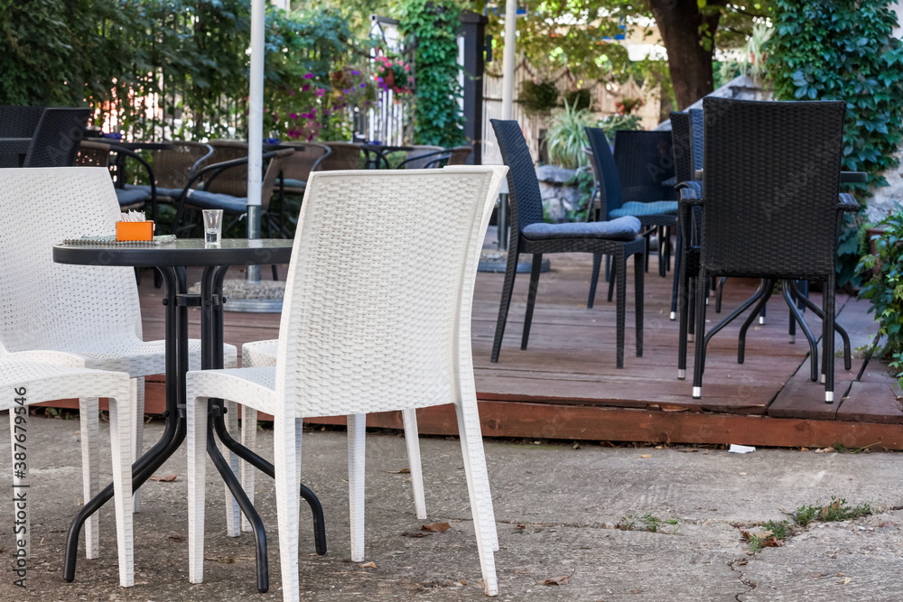 Emtpy chairs and tables in the garden and terrace of a cafe bar restaurant, with nobody to seat and drink, in summer