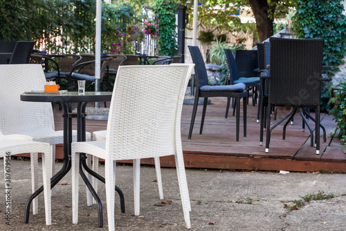 Emtpy chairs and tables in the garden and terrace of a cafe bar restaurant, with nobody to seat and drink, in summer