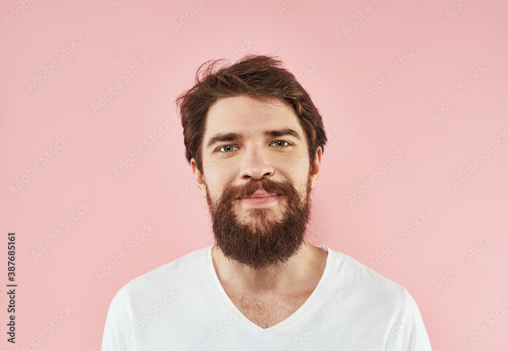 Portrait of a young man with a beard in a white T-shirt on a pink background Portrait of a young man with a beard in a white T-shirt on a pink background