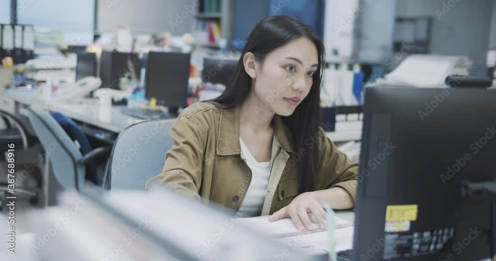 Young asian business woman working on desk in office workplace.A single woman working in the office and she serious about work hard.Desk that looks messy. Young asian business woman working on desk in office workplace.A single woman working in the office and she serious about work hard.Desk that looks messy.