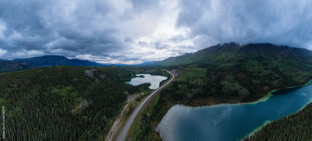 Panoramic View of Lakes from Above surrounded by Forest, alongside Scenic Road at Twilight. Aerial Drone Shot taken in Canadian Nature. Klondike Highway, South of Whithorse, Yukon, Canada. Panoramic View of Lakes from Above surrounded by Forest, alongside Scenic Road at Twilight. Aerial Drone Shot taken in Canadian Nature. Klondike Highway, South of Whithorse, Yukon, Canada.