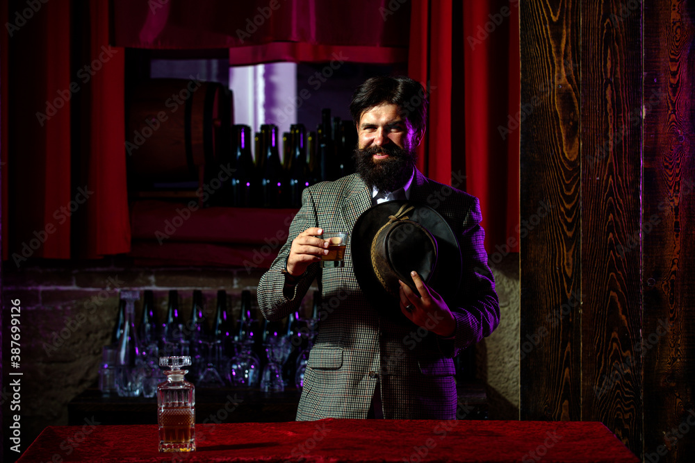 Happy bearded man with glass of brandy or whiskey. Bearded hipster in bar.