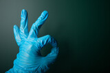 Ok sign hand in blue medical glove on dark background