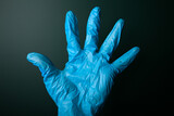 Open hand in blue medical glove on dark background