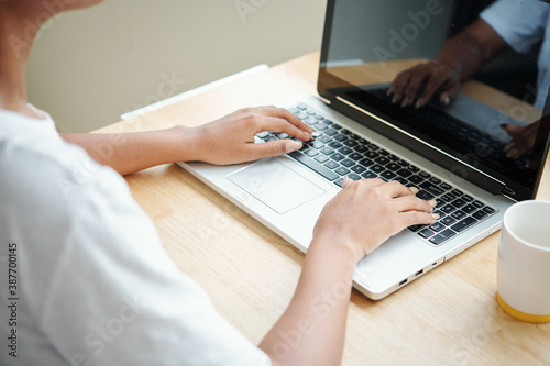 Close-up image of young woman working on laptop, programming or answering e-mails