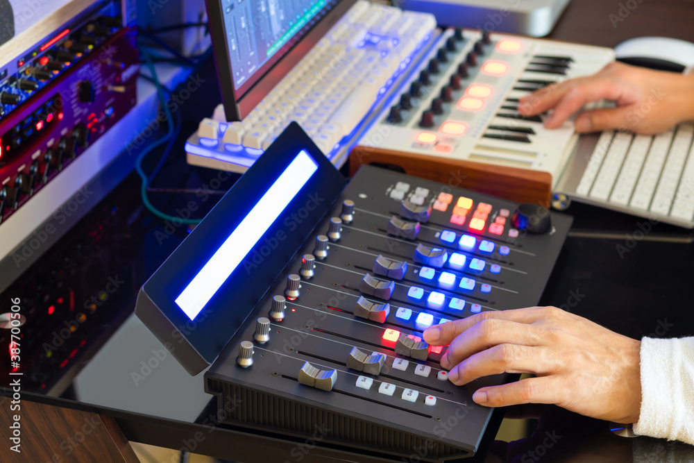 Sound engineer hands adjusting volume on digital audio control surface for mixing audio tracks on computer. Post production, broadcasting, recording concept Sound engineer hands adjusting volume on digital audio control surface for mixing audio tracks on computer. Post production, broadcasting, recording concept