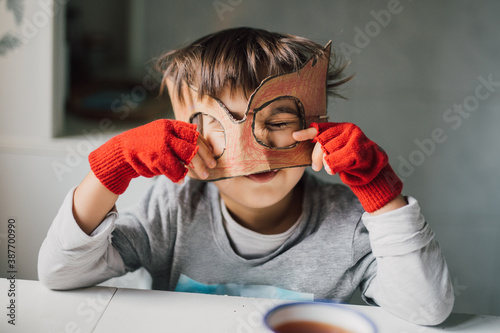 Fényképezés Cute kid in disguise with DIY  cardboard superhero mask at home