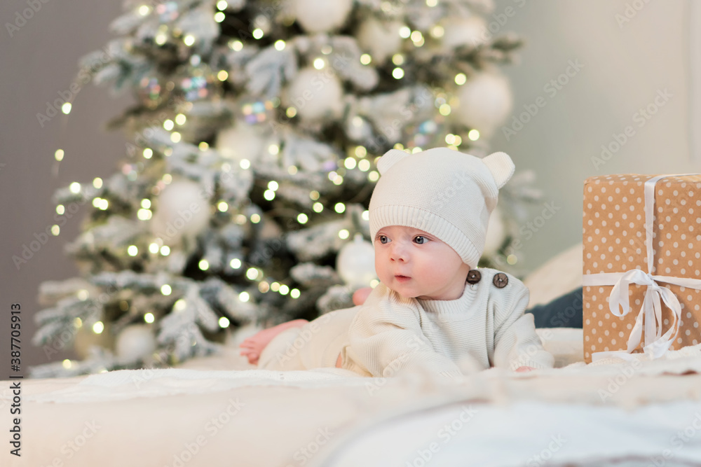 Tiny little child celebrates its first Christmas among gift boxes and Christmas lights. Christmas eve at home Tiny little child celebrates its first Christmas among gift boxes and Christmas lights. Christmas eve at home