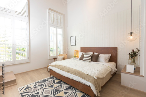 Master bedroom in rustic style with minimalist white double bed and hanging lamp.