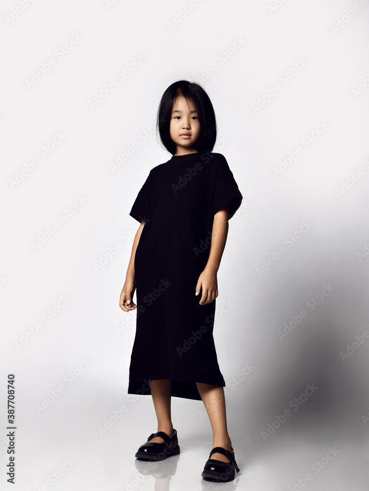 Φωτογραφία Full-growth portrait of self-confident asian kid girl in black long t-shirt dres