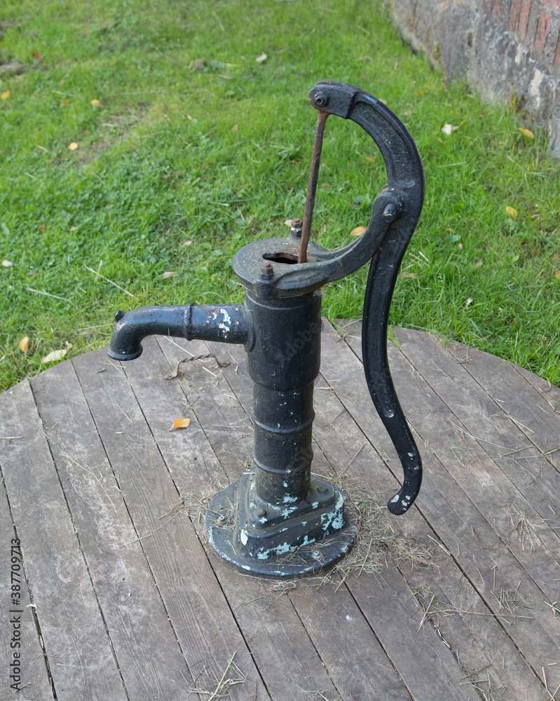 Old hand pump for collecting water on a wooden platform Old hand pump for collecting water on a wooden platform