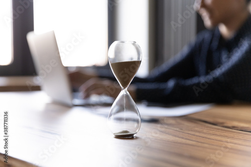 Photos Close up crop of hourglass on wooden home office table count measure time