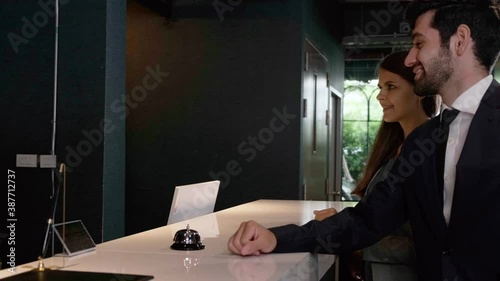 couple celebrating their anniversary checking in at hotel reception female receptionist asking for and checking their passports . He receives a key card from the room, business trip..