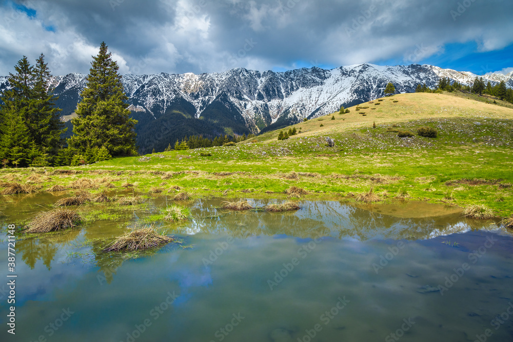 Small lake and snowy mountains in background, Piatra Craiului, Romania
