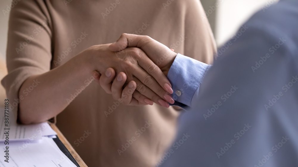 Crop close up of diverse businesspeople shake hands greeting or get acquainted at meeting in office. Business partners or colleagues handshake close deal or make agreement at successful negotiations.