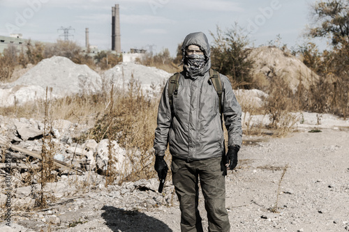 dangerous man stalker in a mask, hooded, holding a gun in his hand