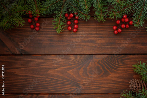 Pine branches with cones and red berries on a wooden background. Christmas background. Happy New Year! Copy space for your text.