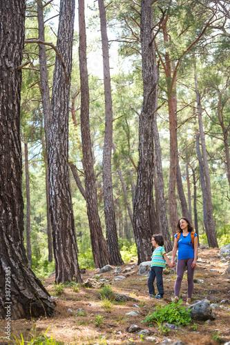 A woman walks with her son through the forest.