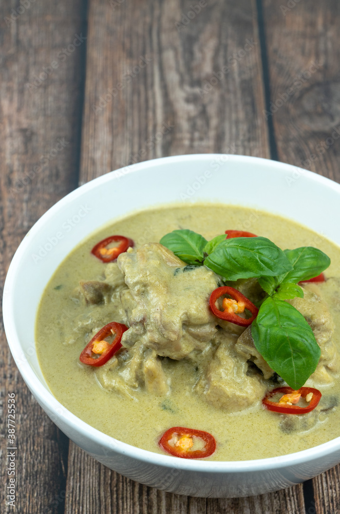 Traditional Thai cuisine, green curry chicken in white bowl over wooden background Traditional Thai cuisine, green curry chicken in white bowl over wooden background