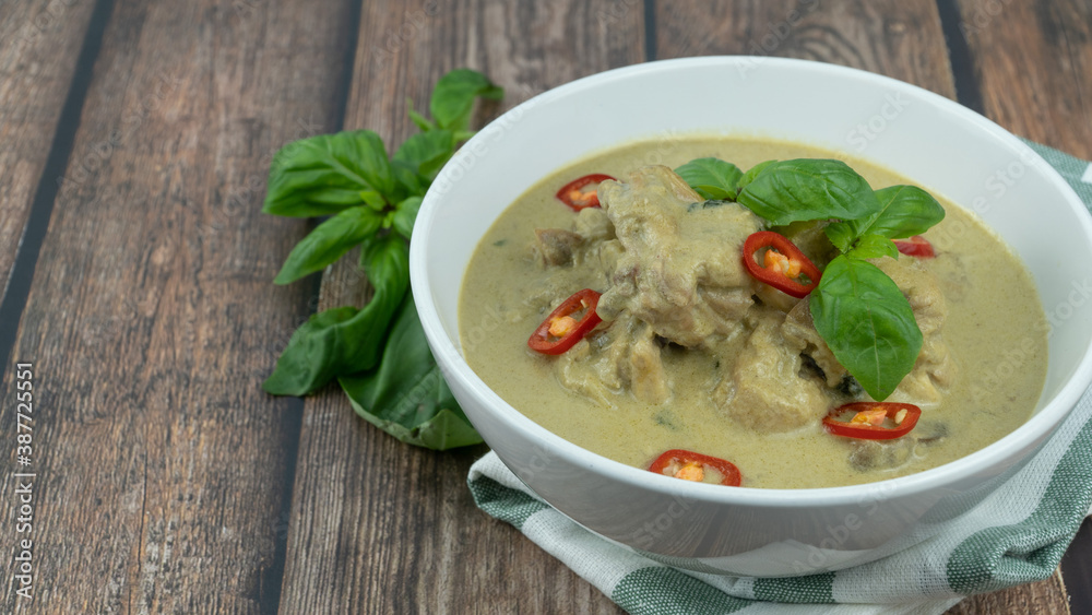 Traditional Thai cuisine, green curry chicken in white bowl over wooden background Traditional Thai cuisine, green curry chicken in white bowl over wooden background