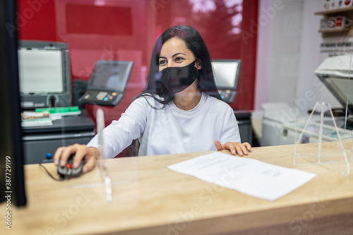 Beautiful woman wearing face mask and using computer in copy shop