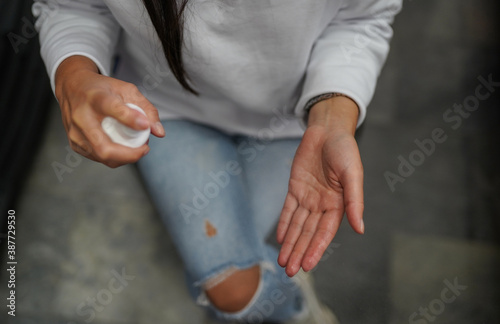 Young woman holding hand sanitizer and spraying on hand