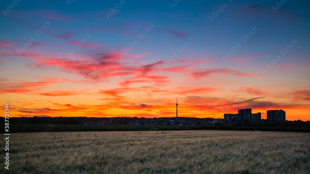 Germany, Stuttgart, Dramatic red glowing sunset sky  above fields and tv tower Fernsehturm in summer at blue hour