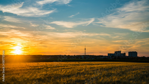 Germany, Stuttgart, Romantic orange sunset sky above fields and tv tower Fernsehturm in summer evening season