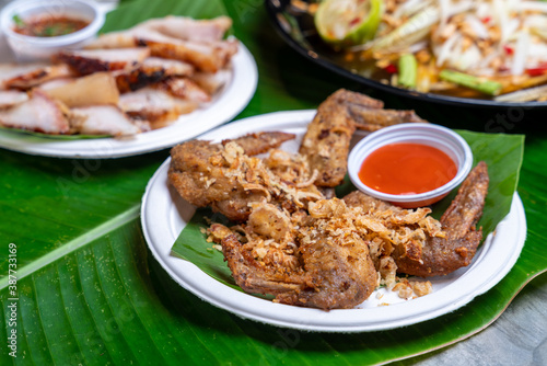 Street food in thailand oil fried chicken wings. Served with tomato on banana leaf