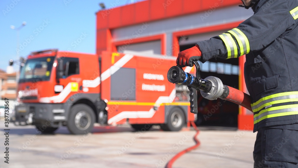  A fireman keeps fire hose for training. Close up shot. Fire station background.