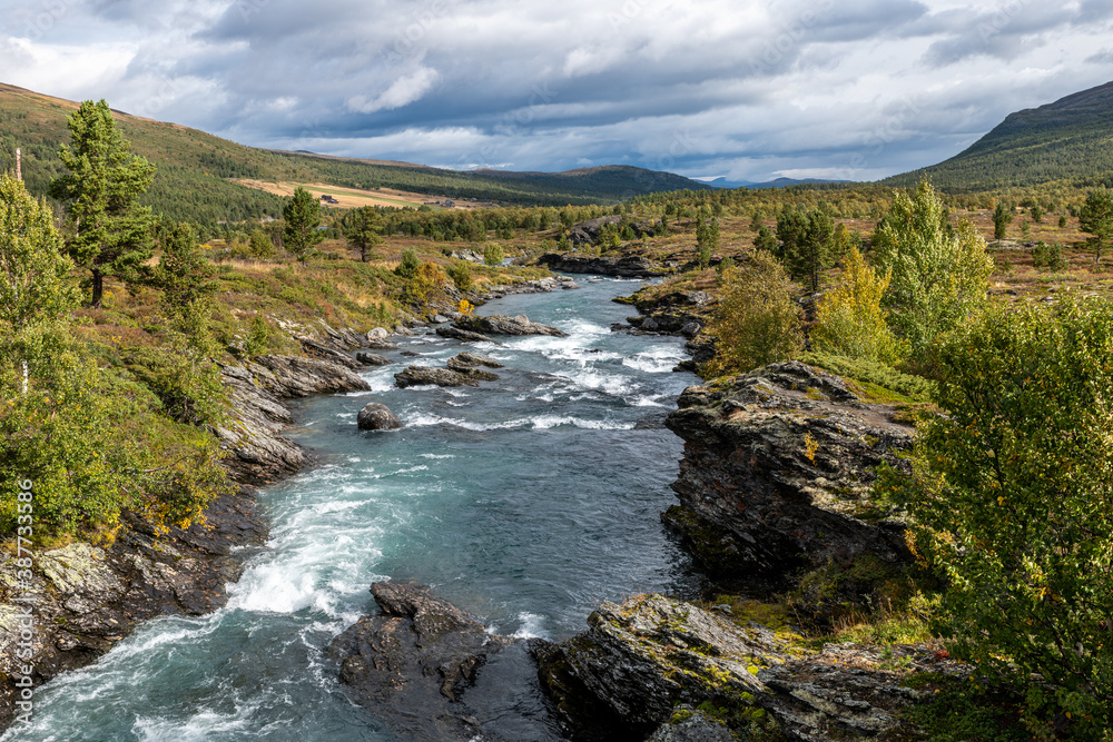 river in the mountains, with trees clouds in autumn