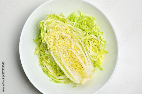 Fresh chinese cabbage salad in bowl on white table background. Vegan food lifestyle. Top view.