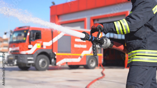 Photo A fireman keeps fire hose and extinguishes fire for training