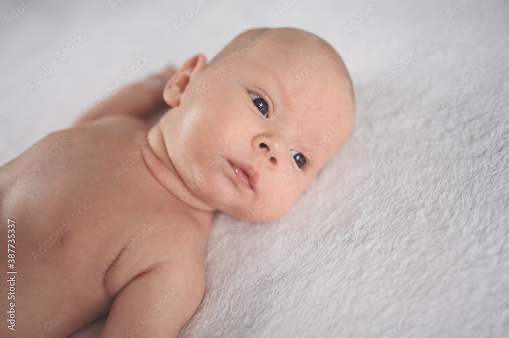 Cute emotional smiling funny newborn boy laying on bed top view. Baby facial expressions. Cute emotional smiling funny newborn boy laying on bed top view. Baby facial expressions.