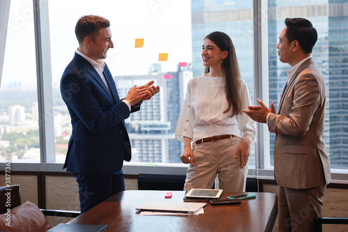Business people standing and talking or discussing or brainstorming in meeting room, team clap hands and admire 
