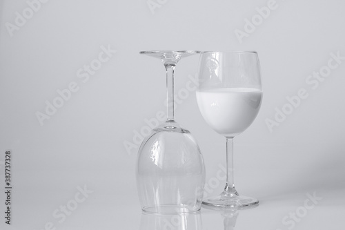 Image of a glass of white drink and an empty glass on a white background