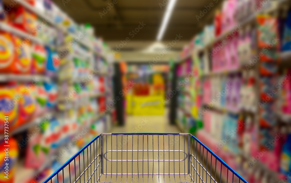 Supermarket corridor with empty blue shopping cart.