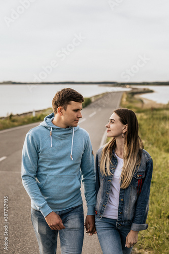 Portrait of romantic couple look to each other and walking along the shore with mountains