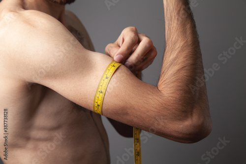 Male biceps and measuring tape