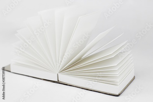 Fan open small unfold notepad with blank light beige pages. Notebook, sketchbook, book. White background