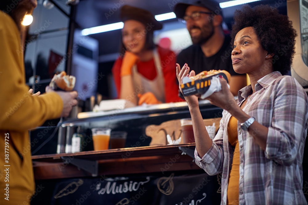 thrilled afro-american woman talking to a beardy guy while eating sandwich. thrilled afro-american woman talking to a beardy guy while eating sandwich.