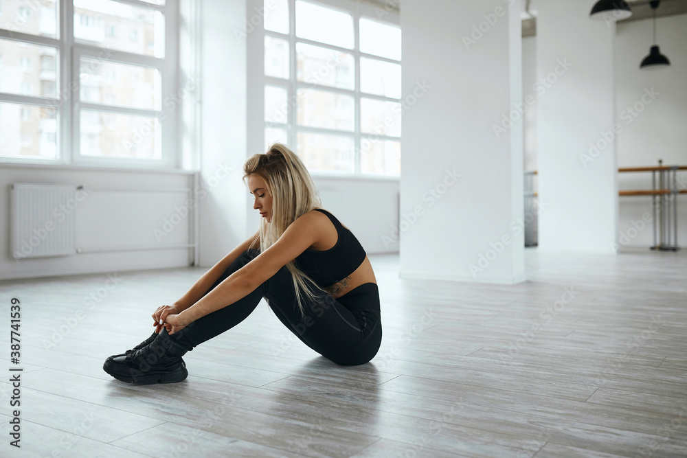 young woman, blonde, sportswoman is engaged in the gym on the mat. the girl shakes the press. the girl, lying on the floor, threw her hands behind her head. the athlete pulls the elbow to the knee