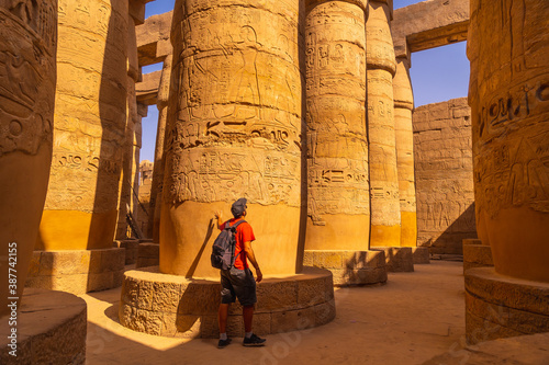 A young tourist walking among the columns with hieroglyphs inside the Karnak Temple, the great sanctuary of Amun. Egypt