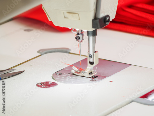 Close up of sewing process on the overlock in the sewing shop. Tailoring industry.. interior of garment factory shop. Closes making atelier with sewing machines.