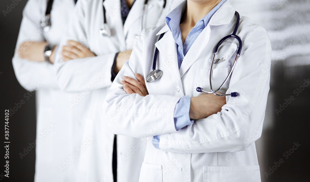 Group of modern doctors standing as a team with arms crossed in hospital office and ready to help patients. Medical help, insurance in health care, best disease treatment and medicine concept Group of modern doctors standing as a team with arms crossed in hospital office and ready to help patients. Medical help, insurance in health care, best disease treatment and medicine concept