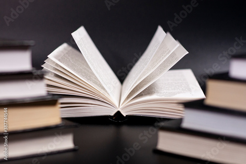 Neat stacks of books on a dark background. Open book. Close up.