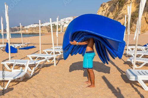 Man carries mattresses on the beach photo