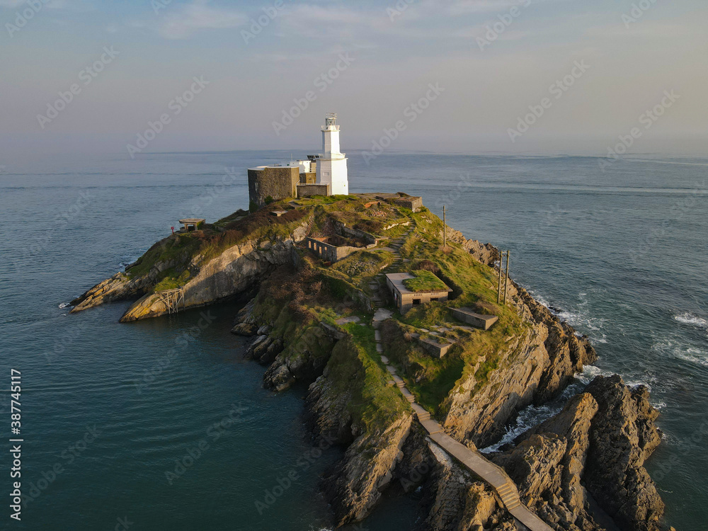 The Mumbles Lighthouse sits on its own island off the coast of South Wales in Gower, near Swansea. Stunning views of the ocean with a misty sky with interesting colours.  