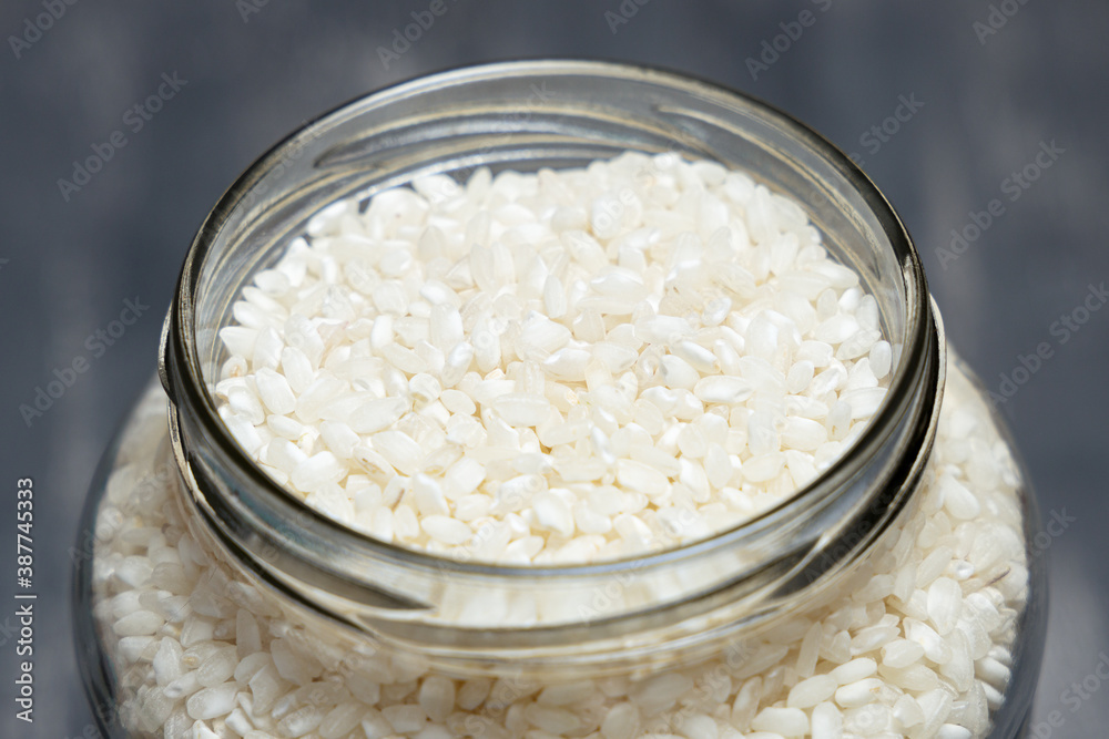 Close up of a big glass jar full of rice placed on a tabletop. Eco friendly concept Close up of a big glass jar full of rice placed on a tabletop. Eco friendly concept