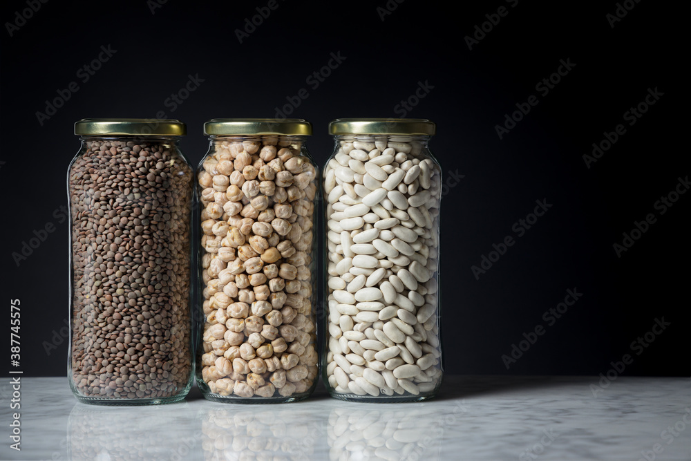 Set of glass jars with various legumes placed on a marble tabletop. Zero waste concept Set of glass jars with various legumes placed on a marble tabletop. Zero waste concept